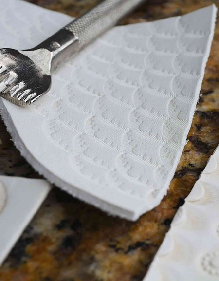 Eco creamy white leather being embossed and stamped