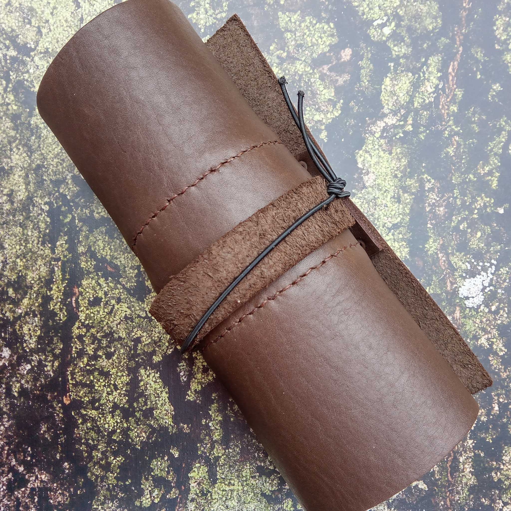 Showing a leather tool roll on a moss and bark effect leather print for photography