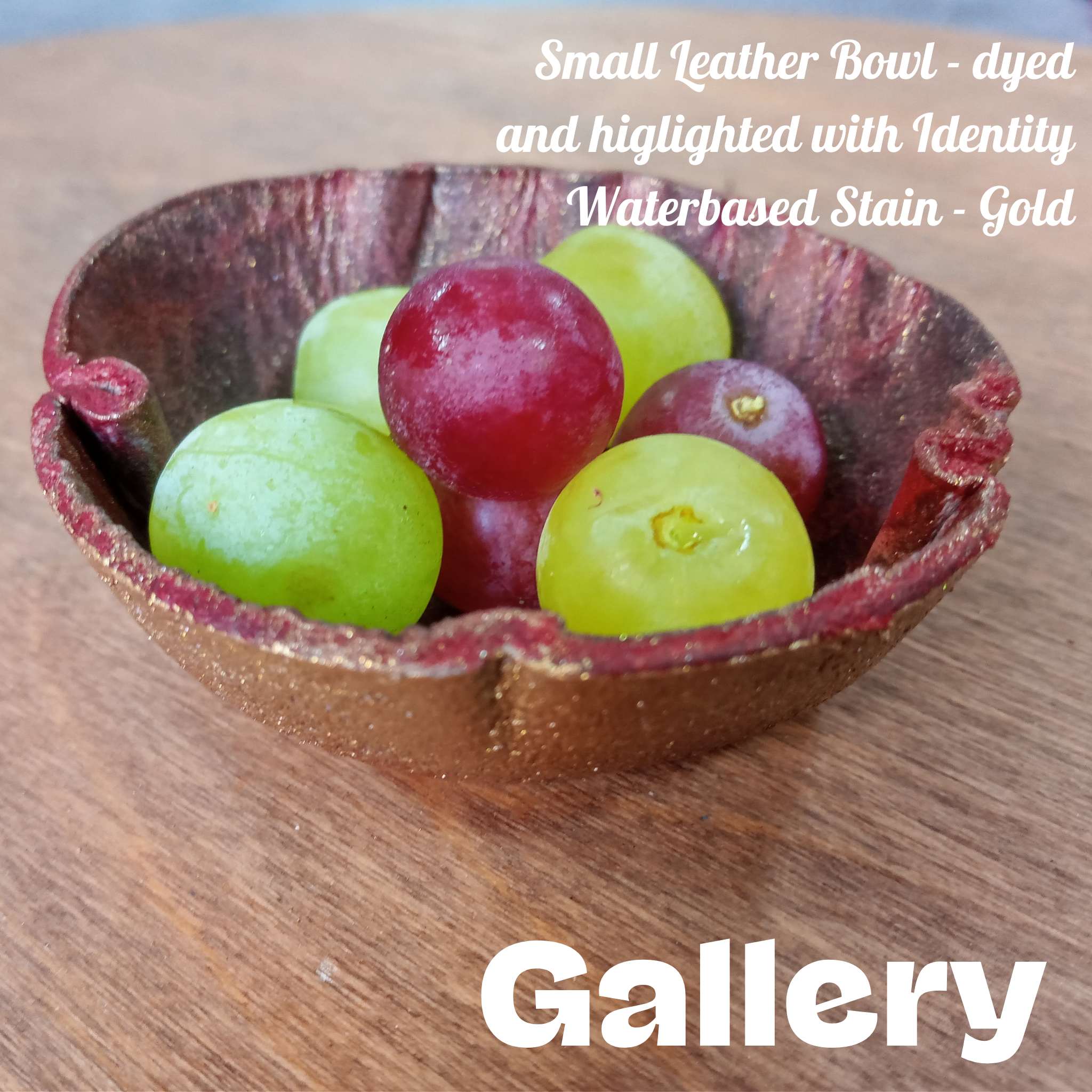 Heat-formed small leather bowl coloured red and gold filled with grapes