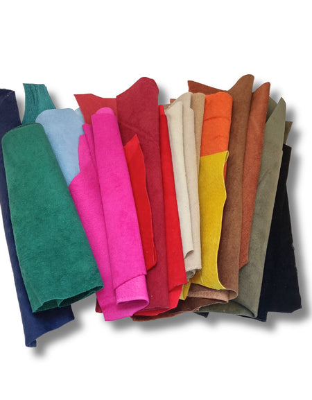 A bag of coloured soft suede leather pieces, hand sized or larger, some narrow and long.