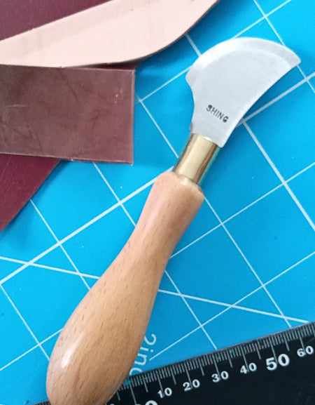 Leather cutting knife with quarter moon head, and hard wood handle, steel blade, hardened by traditional methods, with a razor ground edge. Made in the UK